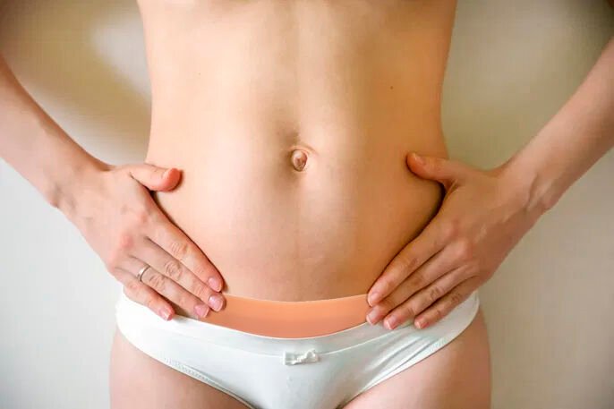 Mulher com a mão na cintura, exibindo a barriga